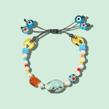 Load image into Gallery viewer, Close-up of freshwater pearl bracelet with larimar, carnelian, and evil eye charms.
