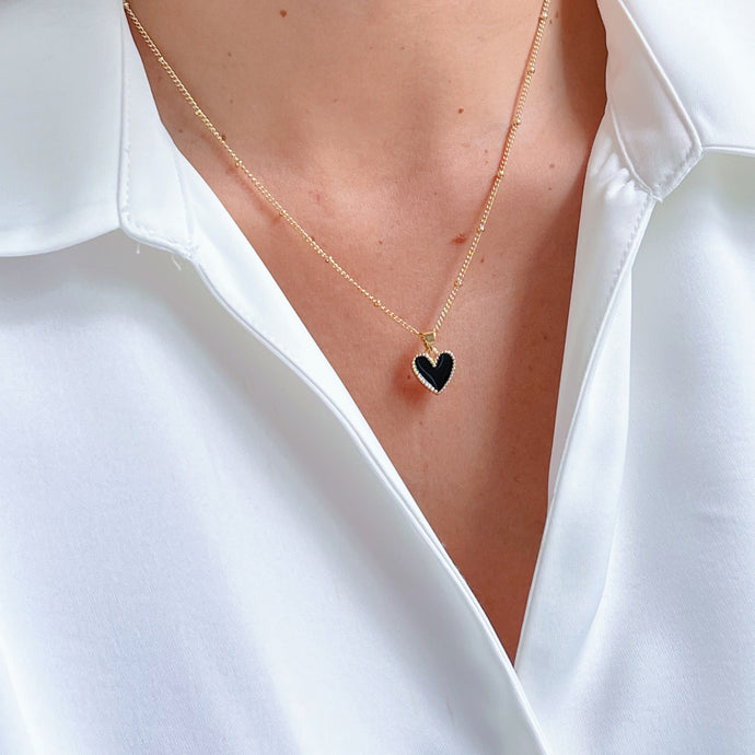 Close-up of Black Enamel Heart Necklace on a gold-plated chain. Stylish and elegant jewelry piece, perfect for everyday wear or special occasions.