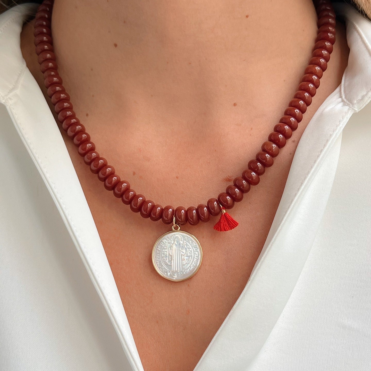 Model wearing brown bead necklace with Saint Benedict pendant