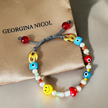 Load image into Gallery viewer, Colorful beaded bracelet laid flat, showing all charms (freshwater pearls, evil eye, mushroom, and smiley face).
