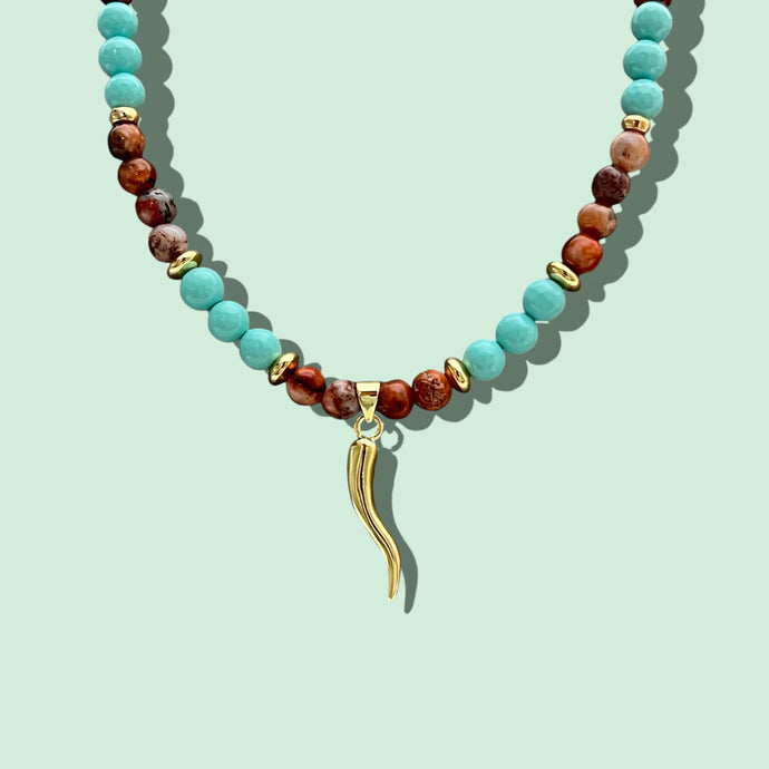 Close-up of Cornicello pendant with earthy tone and turquoise beads.