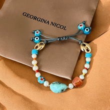 Load image into Gallery viewer, Freshwater pearl bracelet in packaging, highlighting its gemstones and protective charms.
