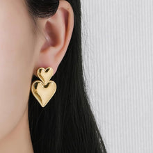 Load image into Gallery viewer, Elegant double heart earrings in 18k gold plated over stainless steel, featuring two hearts, one larger and one smaller, symbolizing love
