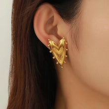 Load image into Gallery viewer, Model wearing large gold heart earrings, showcasing water &amp; tarnish resistance.
