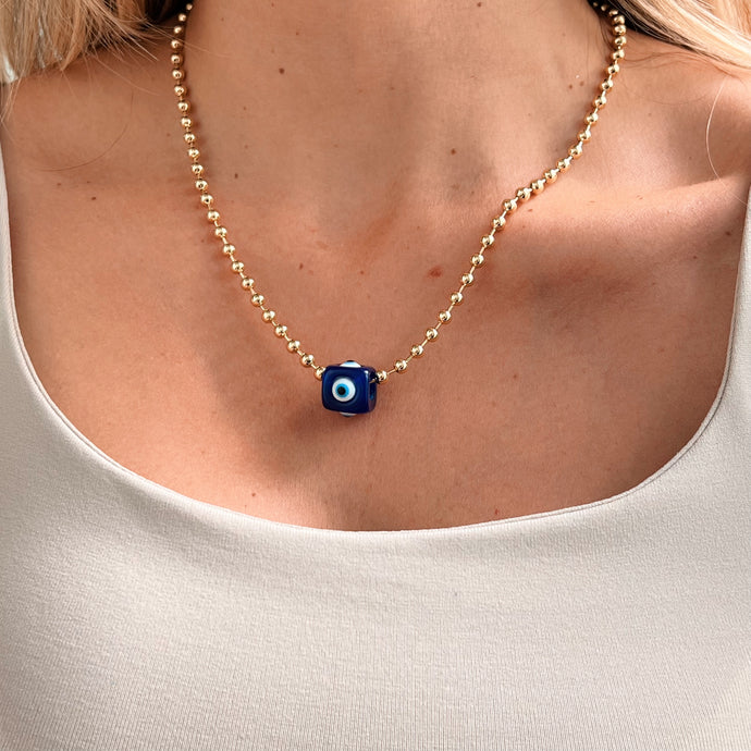 Model wearing evil eye necklace to ward off negative energy.