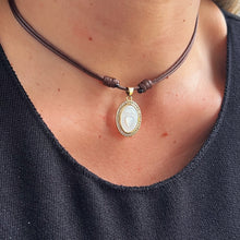 Load image into Gallery viewer, Model wearing the Sacred Heart of Jesus necklace with mother of pearl and CZ details, paired with other gold accessories
