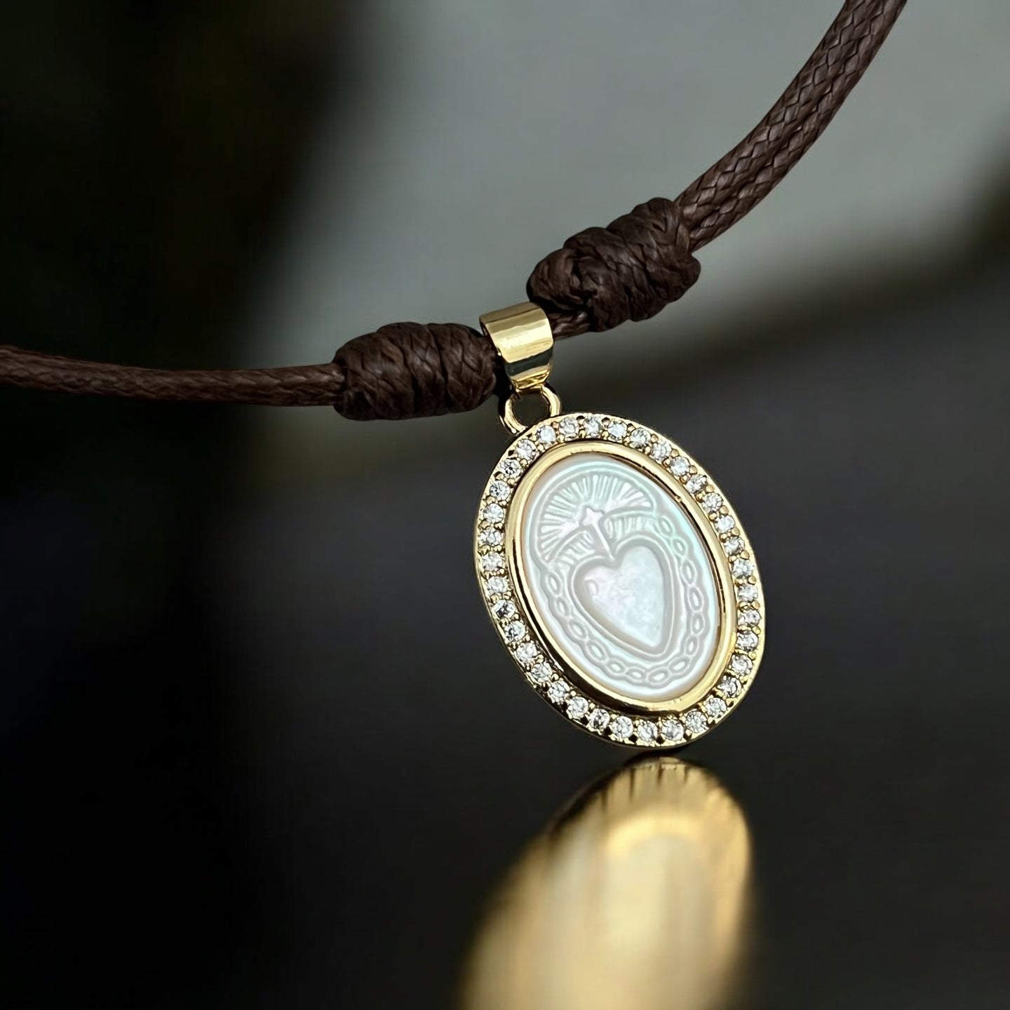 Close-up of mother of pearl Sacred Heart medallion with CZ accents on an adjustable brown cord